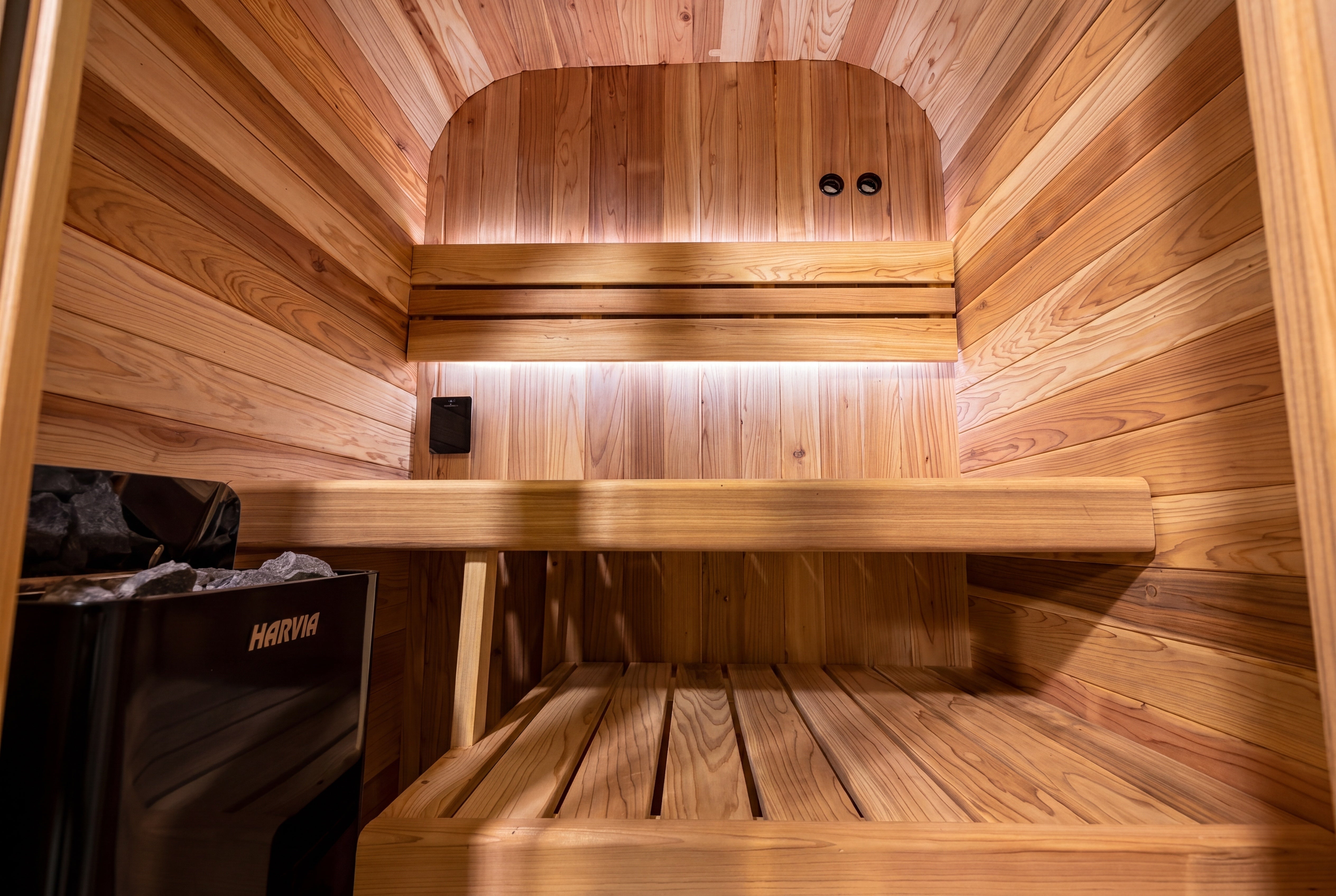 Traditional outdoor sauna heater and cedar bench detail inside Swell Cedar Cube 2