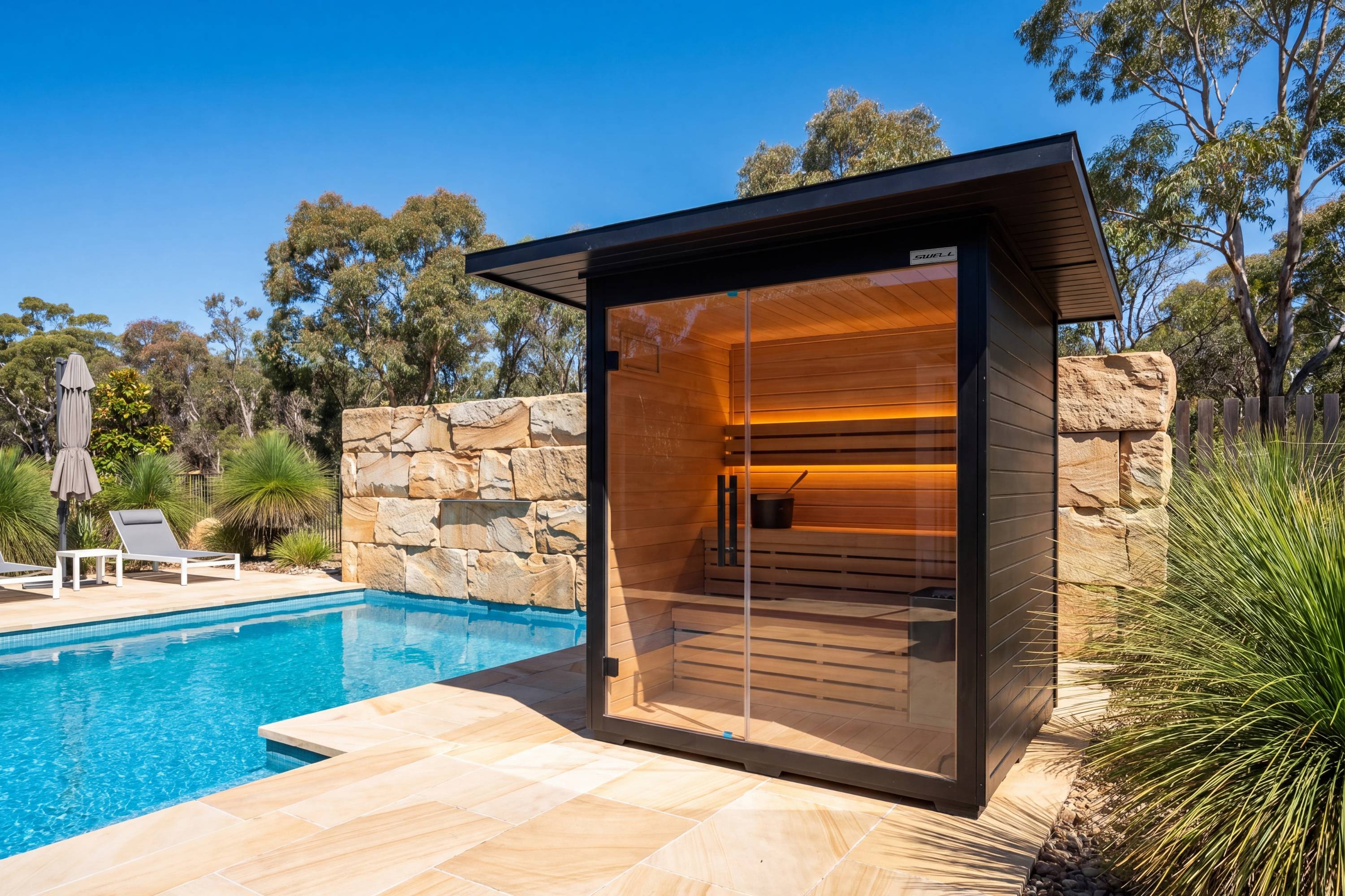 Swell Black Eco 4 outdoor sauna beside pool and stone wall in luxury backyard