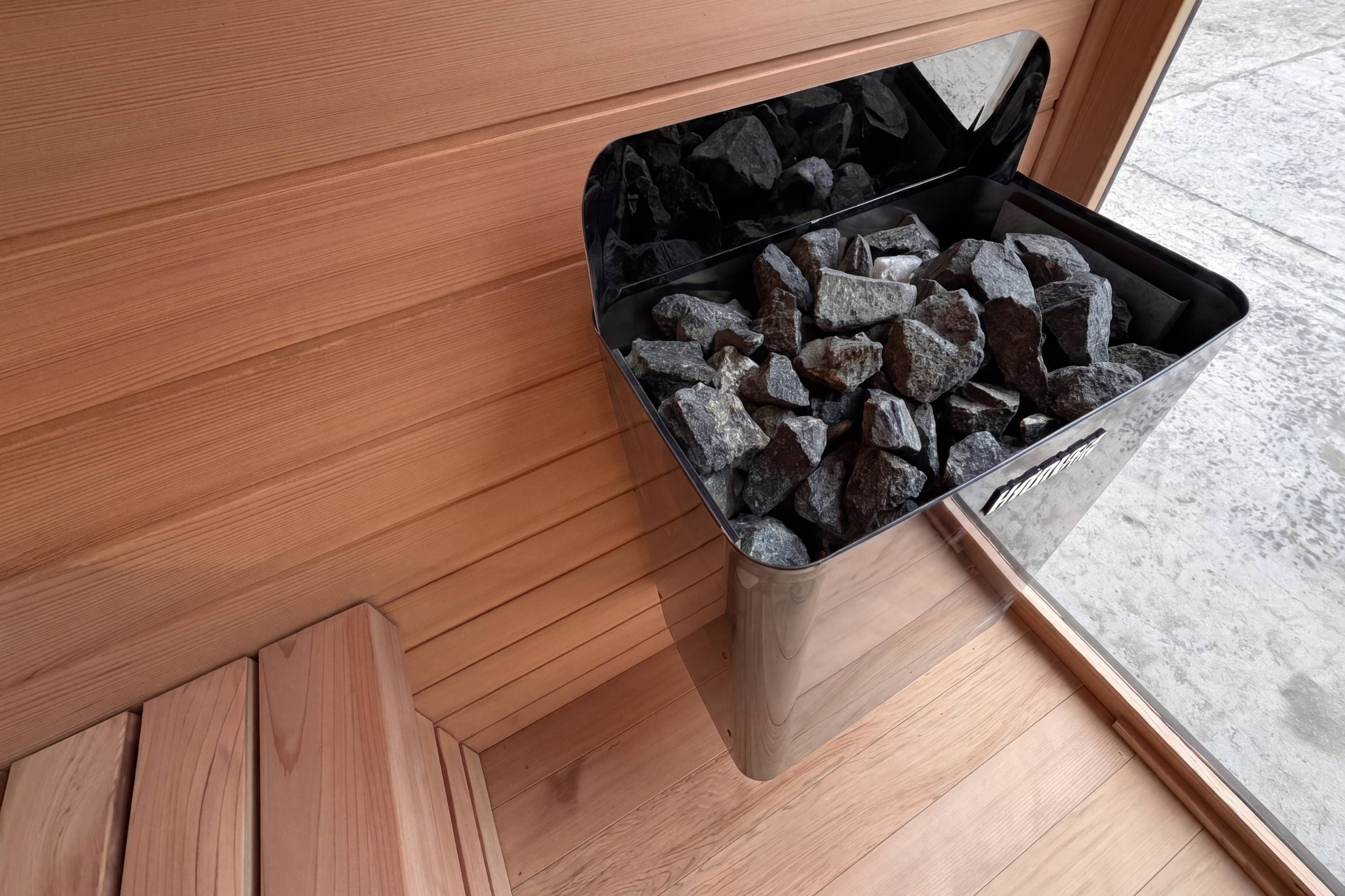 Close-up of Harvia electric sauna heater with hot rocks in Swell Black Eco 4 sauna