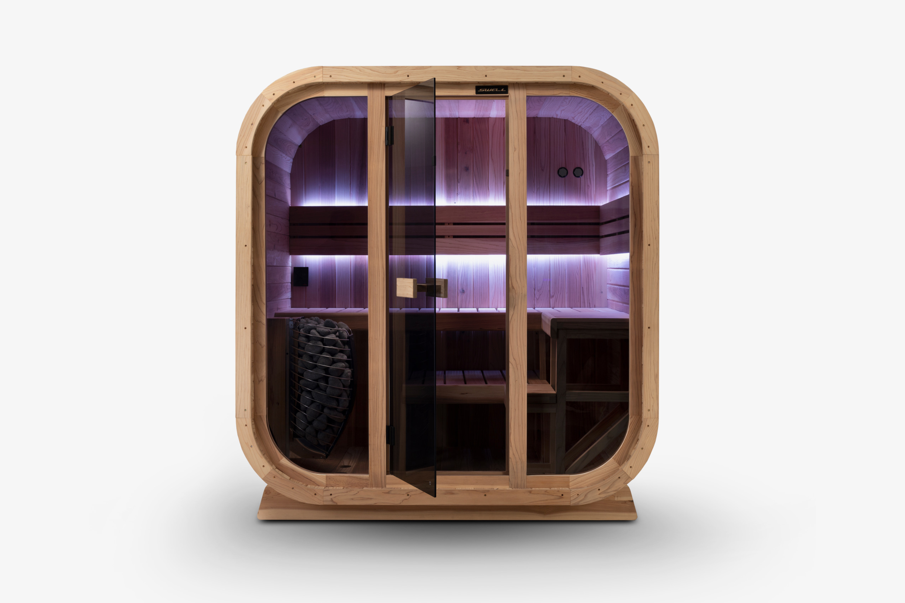 Front view of a Swell Cedar Cube 4 sauna with purple lighting, glass door and stone-filled heater