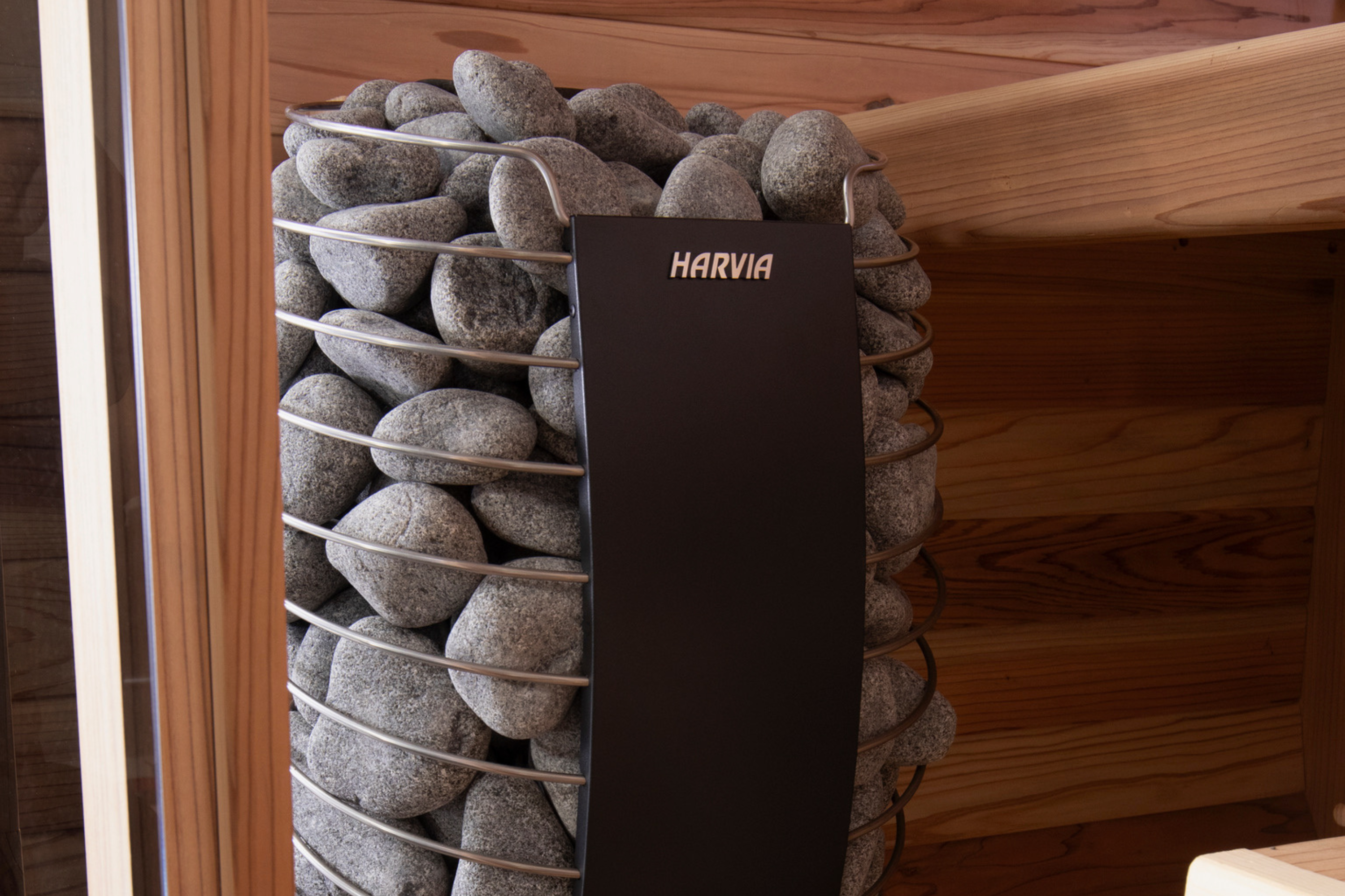Close-up of a Harvia Spirit stone-filled sauna heater inside a Swell Cedar Cube range