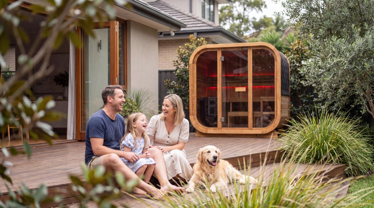 Family and dog relaxing on a deck beside a Swell outdoor sauna